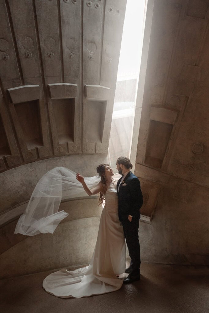 Elegant bride and groom sharing a moment in a modern, concrete architectural setting.