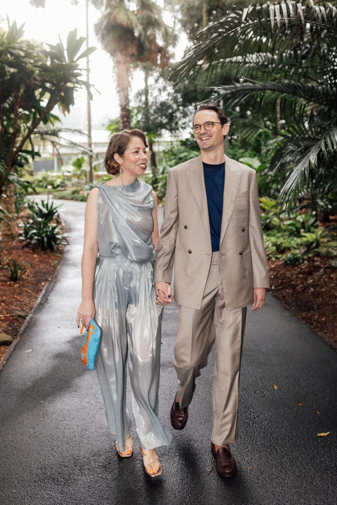 Happy wedding couple walking together in a lush, tropical garden setting.